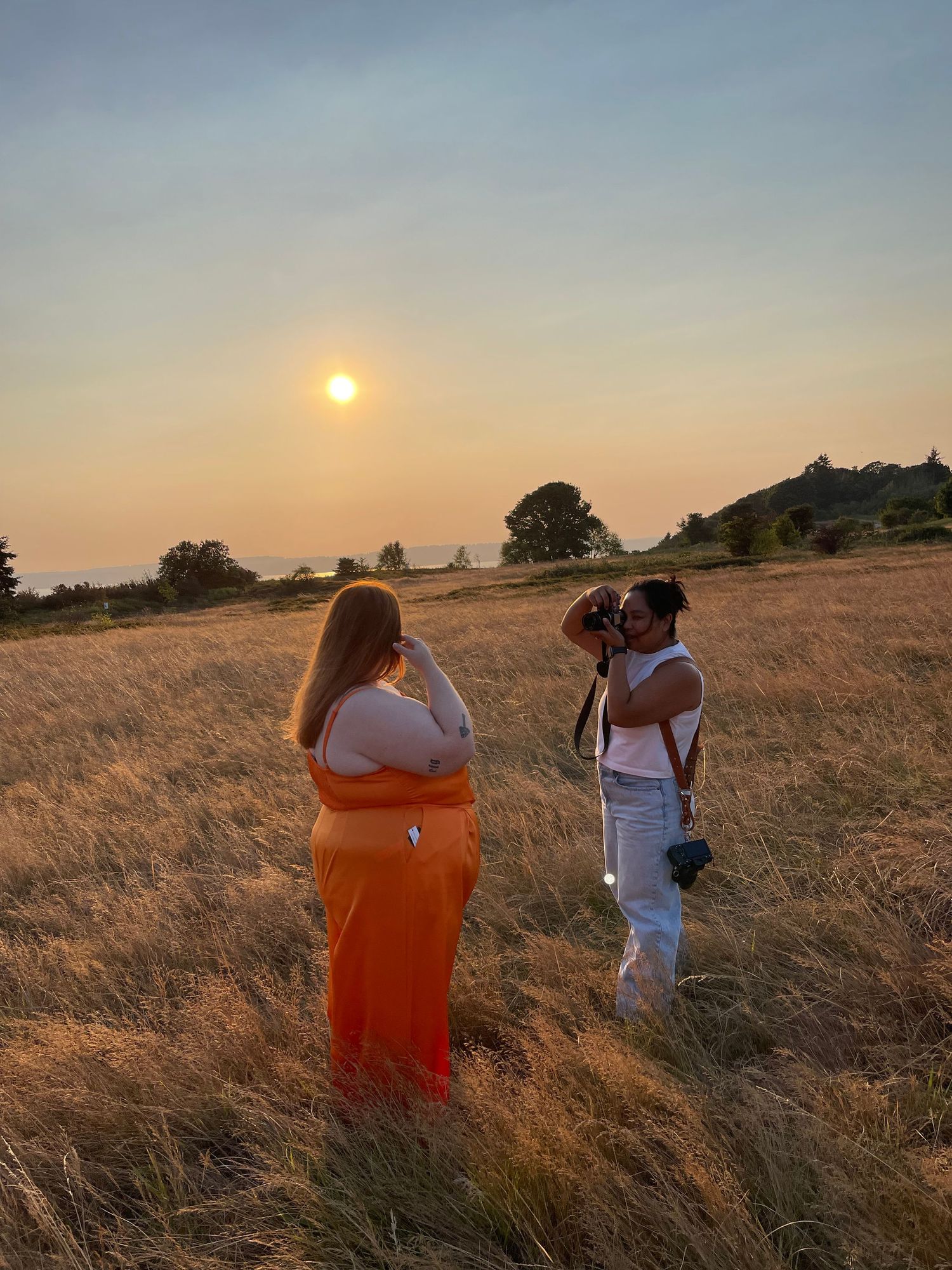 Photographers capturing sunset shots in a golden field with warm evening light.