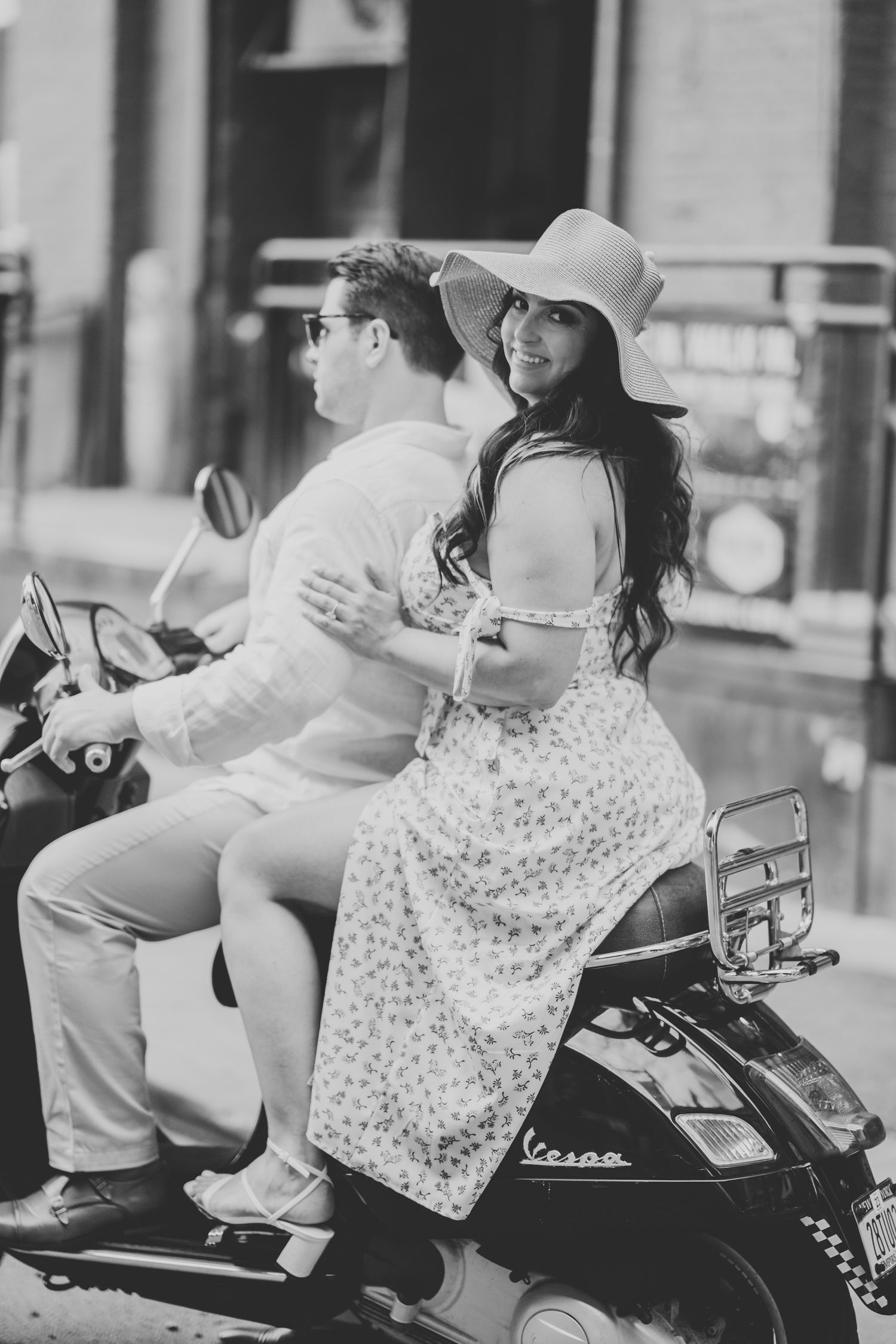 bride sitting behind her groom on their moped looking back at the camera