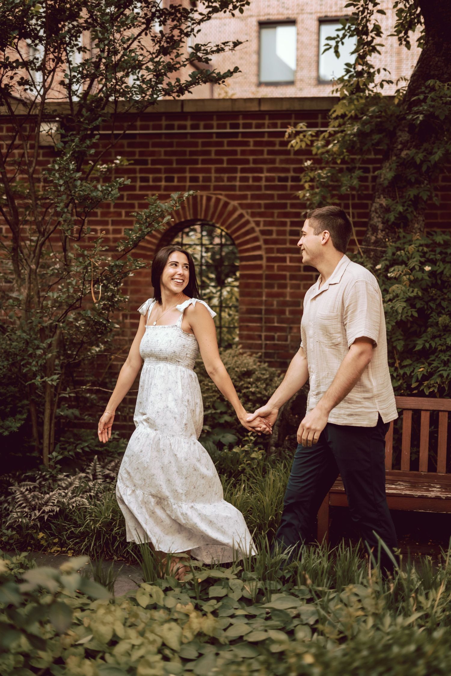future bride leading her fiancé through a small but beautiful city garden