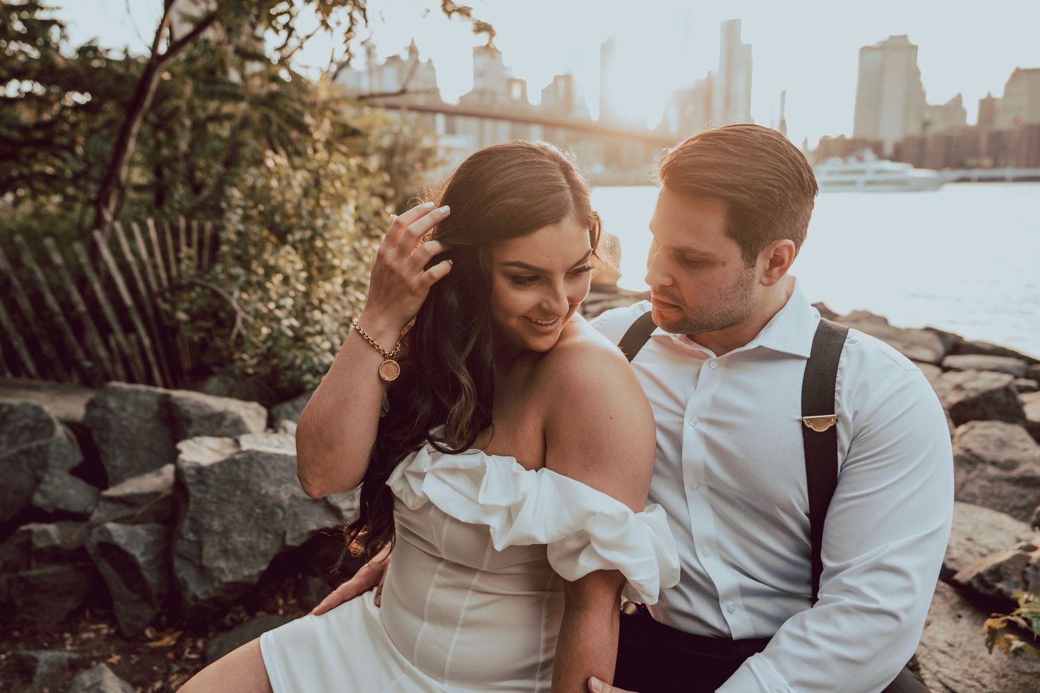 Groom admiring his fiancé's presence at the DUMBO waterfront in Brooklyn during engagement session while sunset casts a 