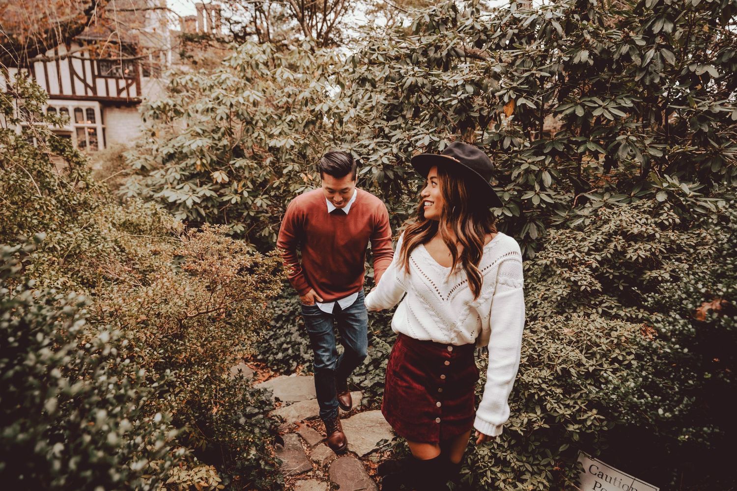 engaged couple walking through the tall bushes of plantingfields arboretum
