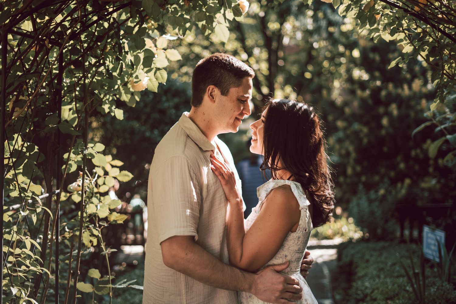 couple hugging each other while showered by sun light seeping through the branches