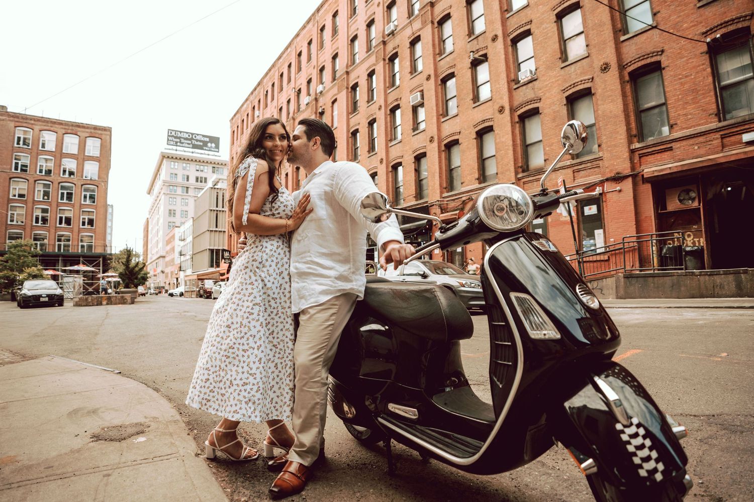 couple getting intimate while sitting on a moped during the engagement session