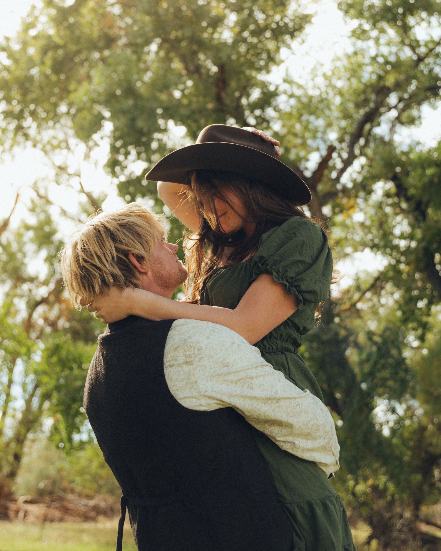 Man lifting his girlfriend in his arms, both smiling at each other with joy and affection.