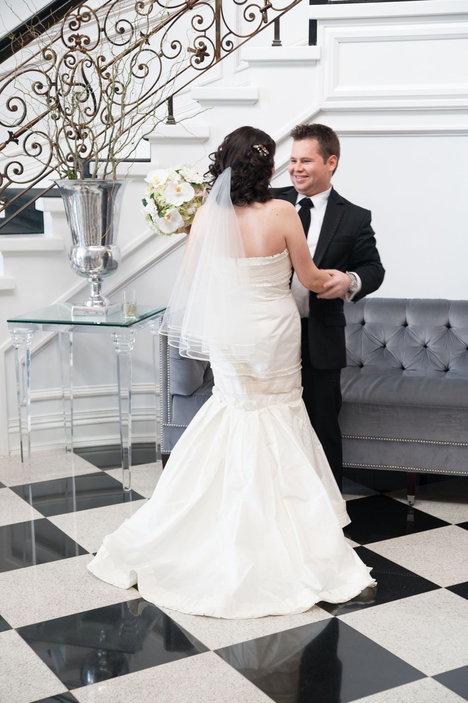 A vogue bride in a couture wedding gown embraces her groom while being during their first-look photoshoot on their weddi