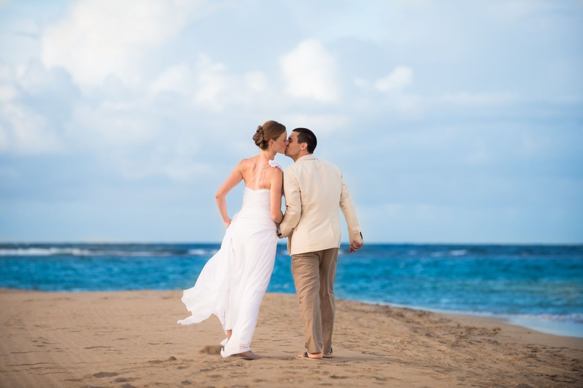A bride and groom are photographed by Lake Placid, NY, wedding photographer, Kevin Young, as they embrace in a kiss walking along the Caribbean beaches of St Kitts during their destination wedding