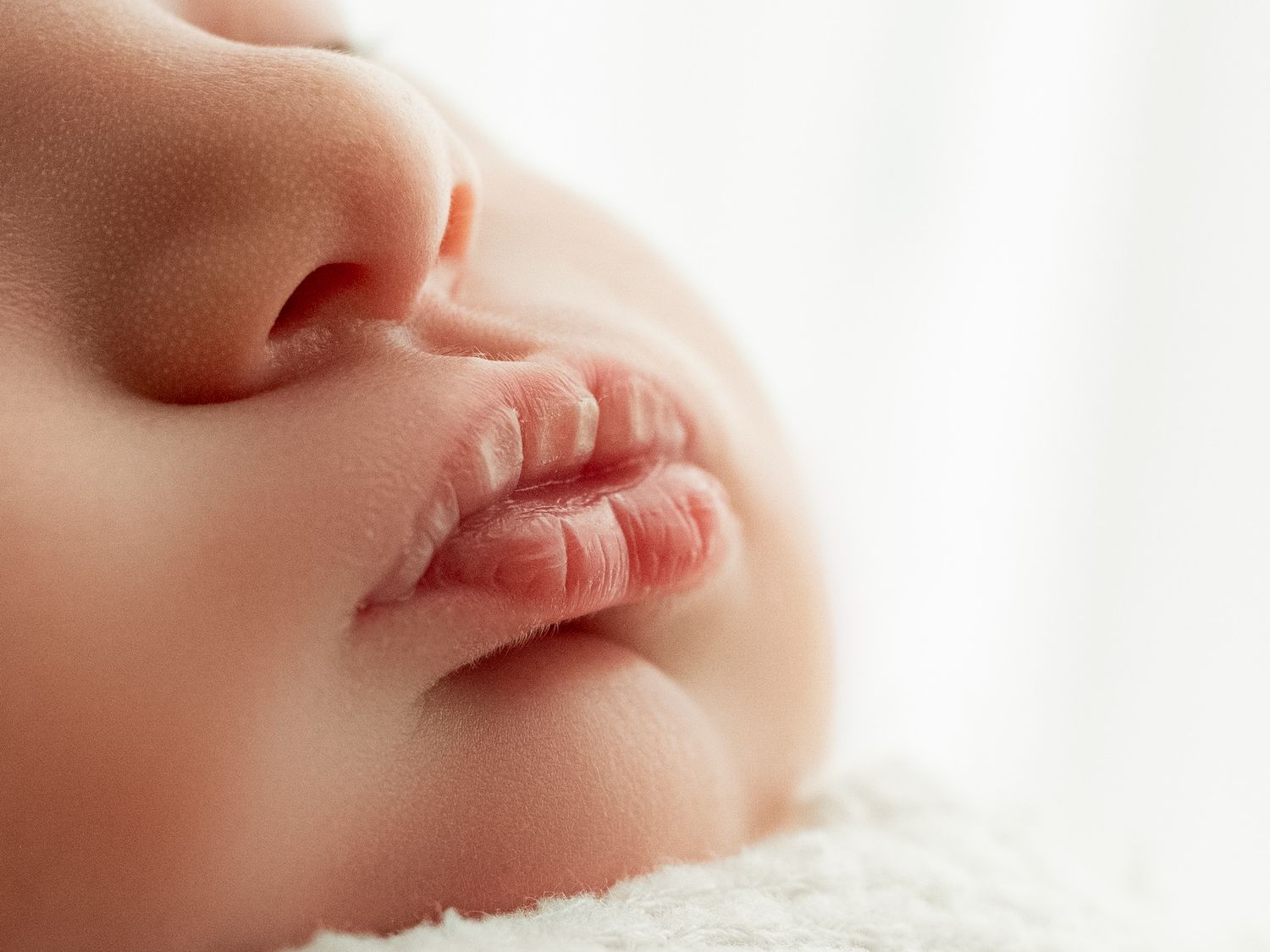 Close-up macro photo of a baby's nose and lips against a white background.