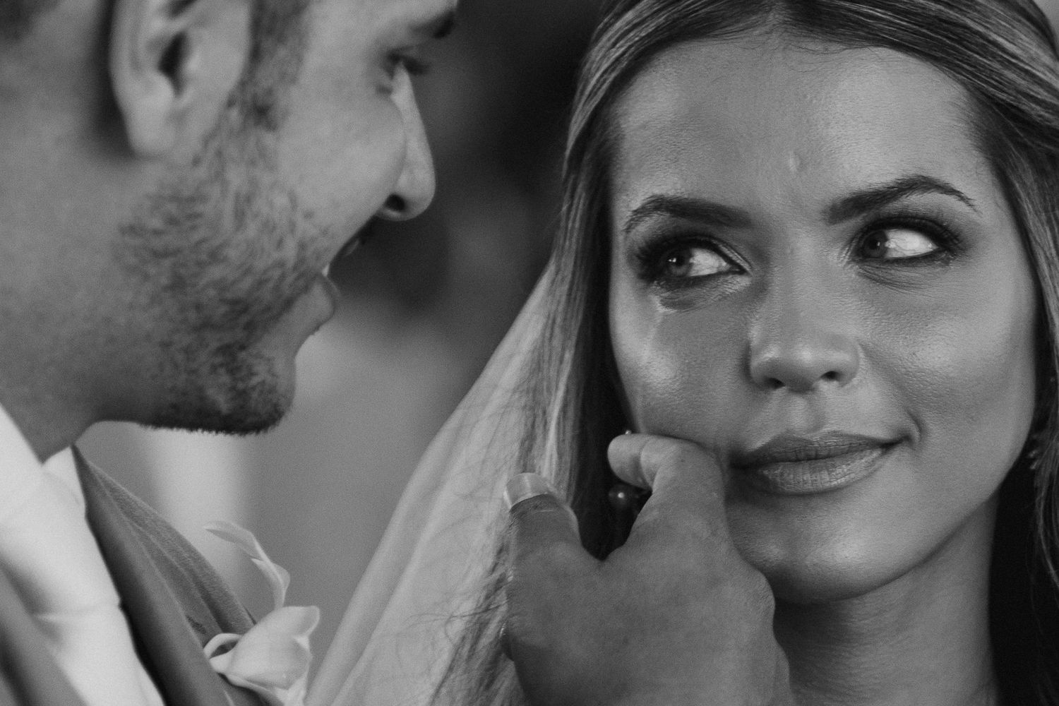 Black and white close-up of groom tenderly touching brides cheek as she gazes up at him.