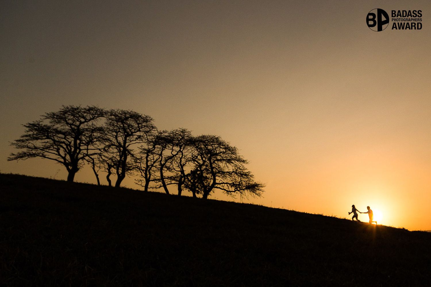 Silhouette of acacia trees and two runners against a golden sunset sky, awarded Badass Photography Award.