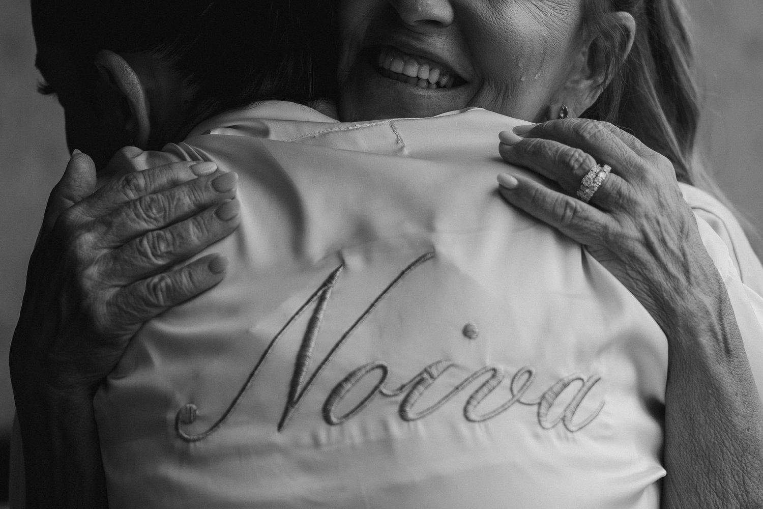 Emotional black and white photo of bride in Noiva robe sharing a warm hug with an older woman.