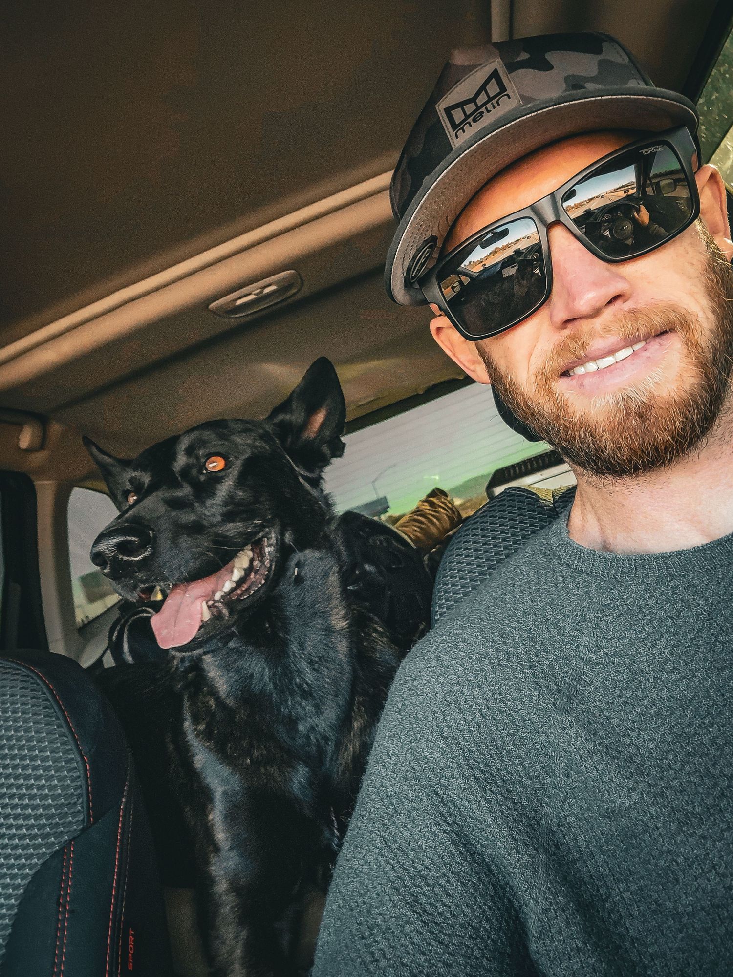 Happy dog and driver take selfie together in car during road trip.