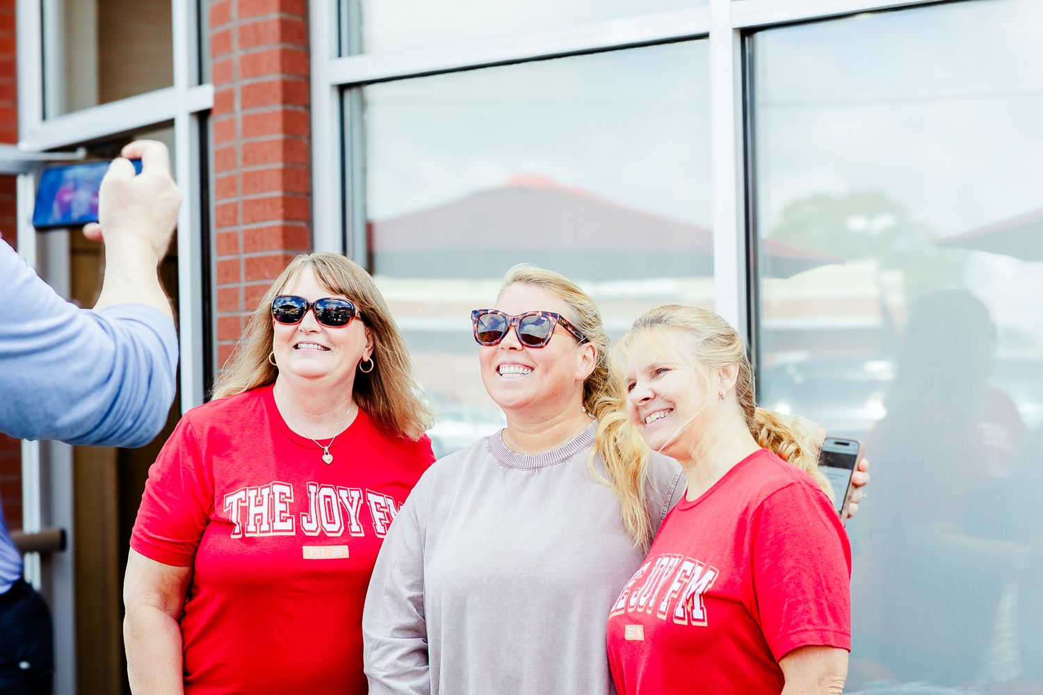 Group of people wearing red shirts gather outside a building entrance for a community event.