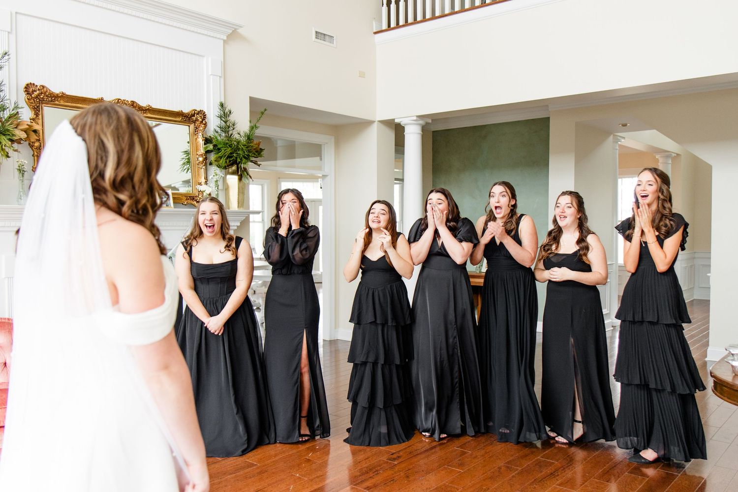A row of bridesmaids in black dresses pose together at a wedding celebration.