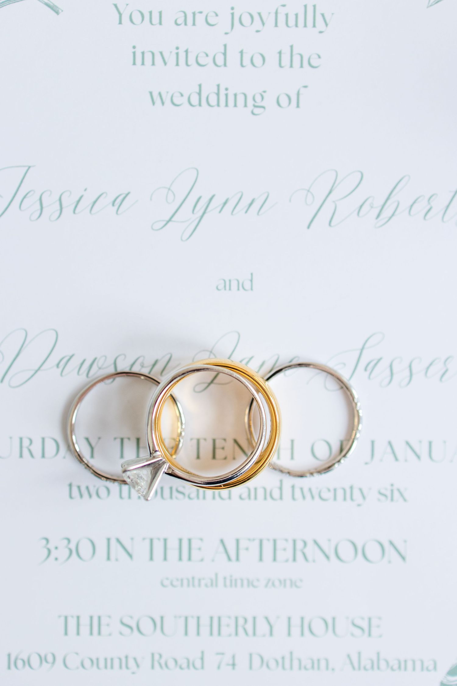 Elegant wedding invitation with mint green calligraphy text and gold wedding rings on white paper.