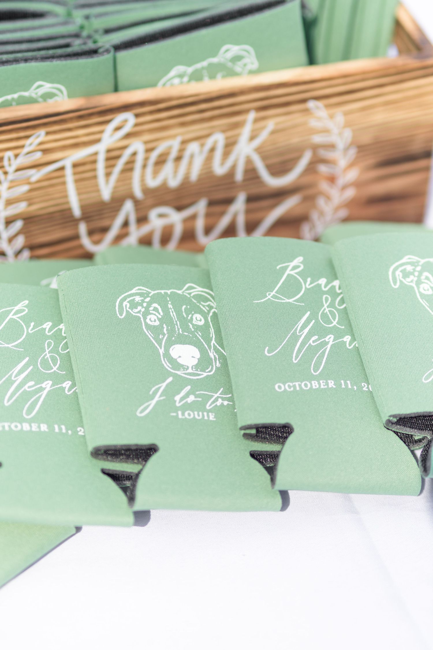 A row of mint green wedding place cards with white calligraphy text displayed on a wooden surface.