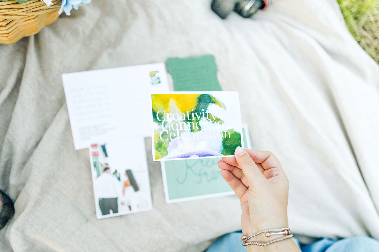 Hands holding and arranging a collection of colorful greeting cards and stationery on a white surface.