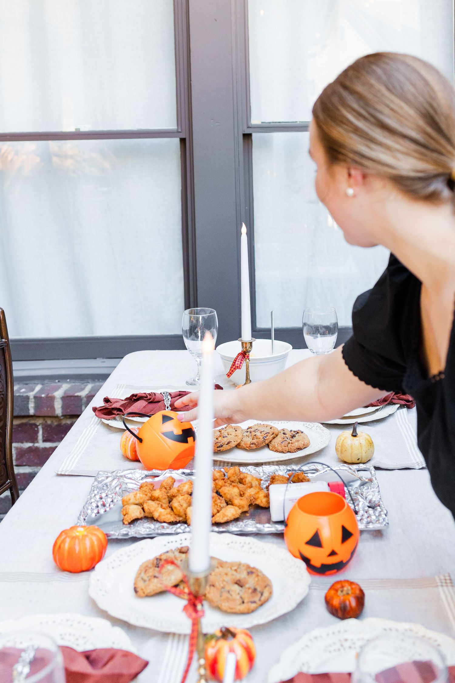 A festive Halloween table setting with cookies, pumpkins and candles as someone prepares for a seasonal gathering.