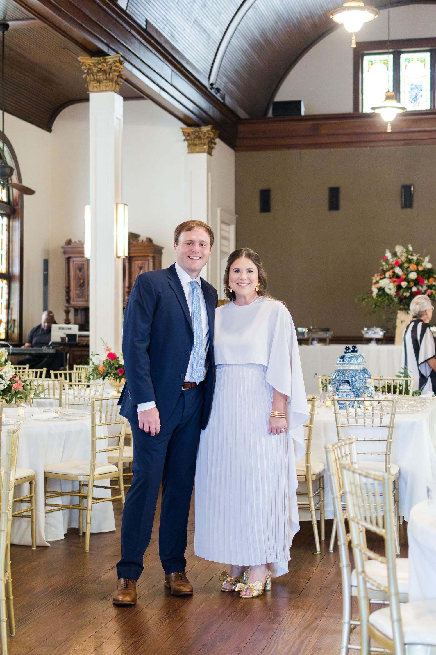 Reception venue interior decorated with white chiavari chairs and floral centerpieces for an elegant wedding celebration.