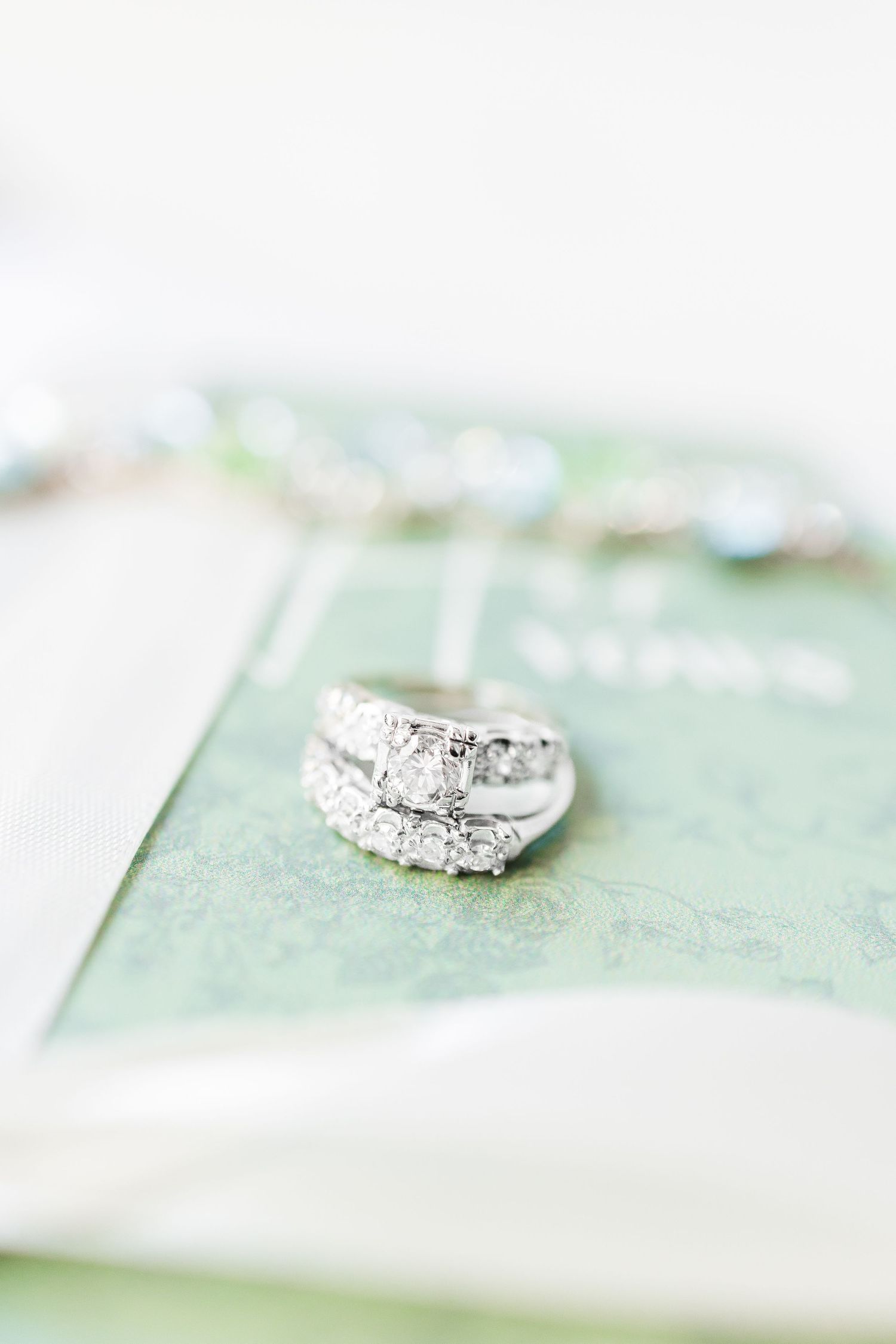 Elegant diamond engagement ring set on a soft mint green background with delicate details in focus.