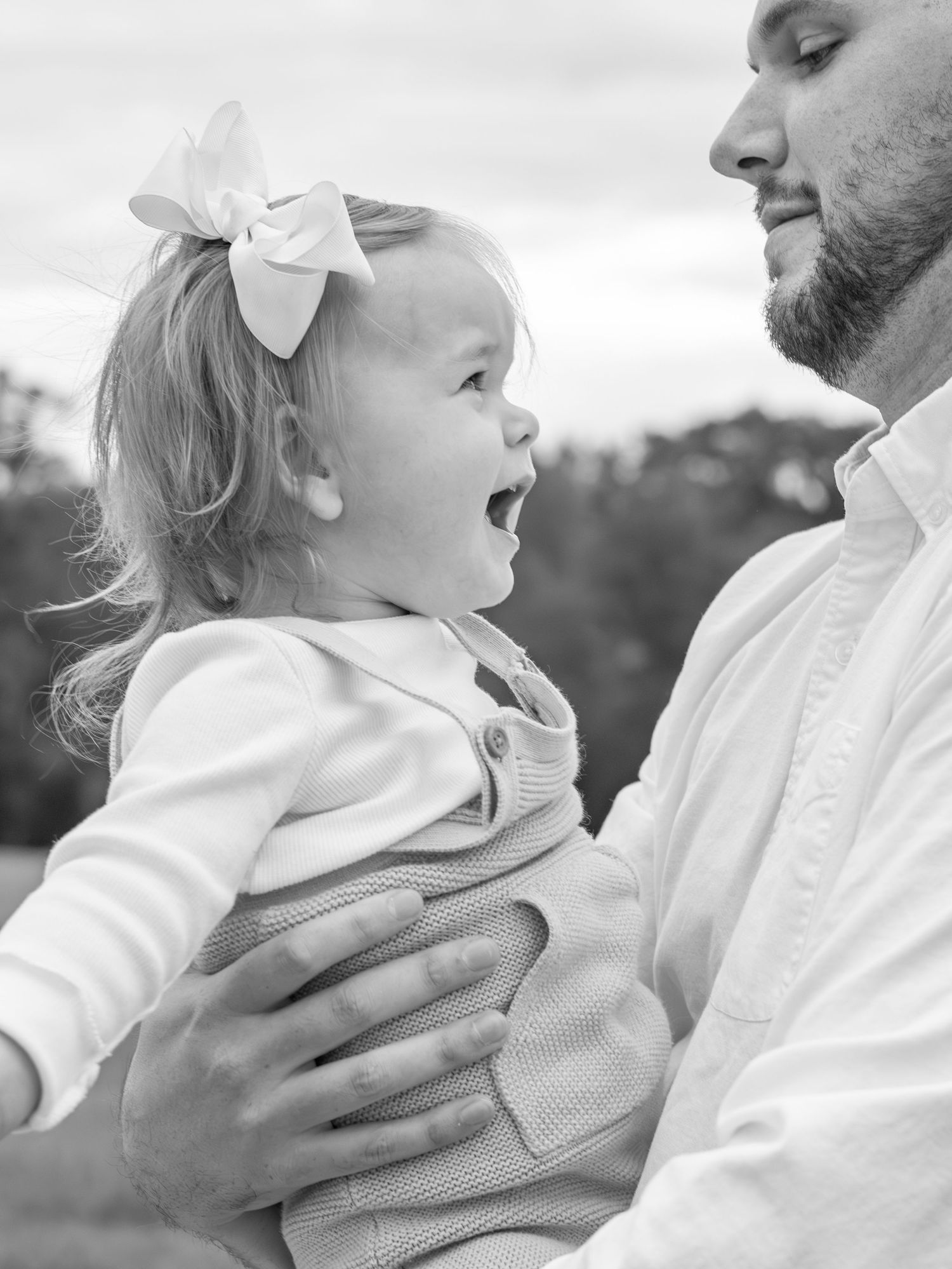 Black and white portrait series showing tender moments between parent and child with white bow accessory.
