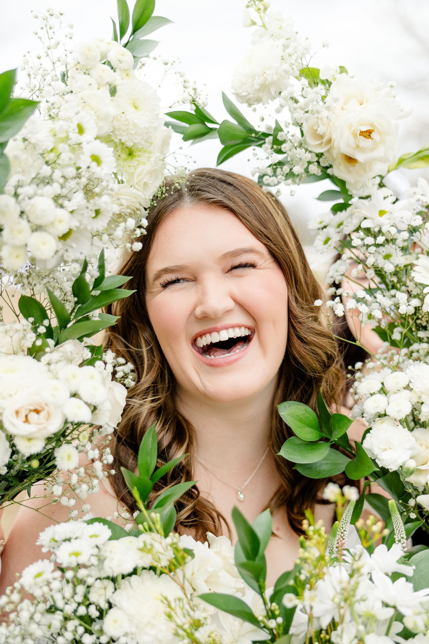 A joyful portrait surrounded by delicate white flowers and green foliage creates a dreamy spring atmosphere.
