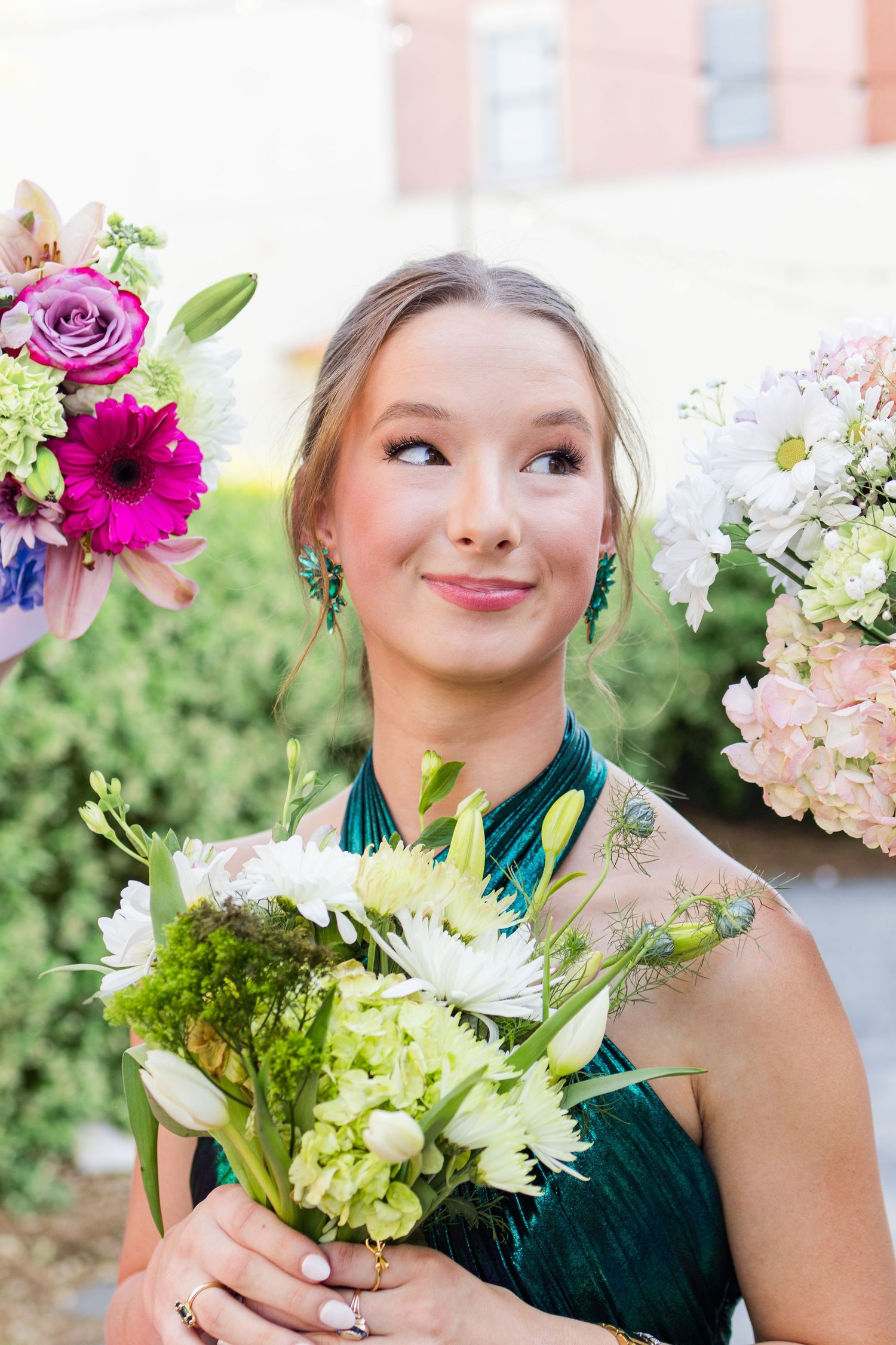 Bridesmaid with floral bouquet composed of green hydrangeas, pink roses and purple dahlias against garden background.