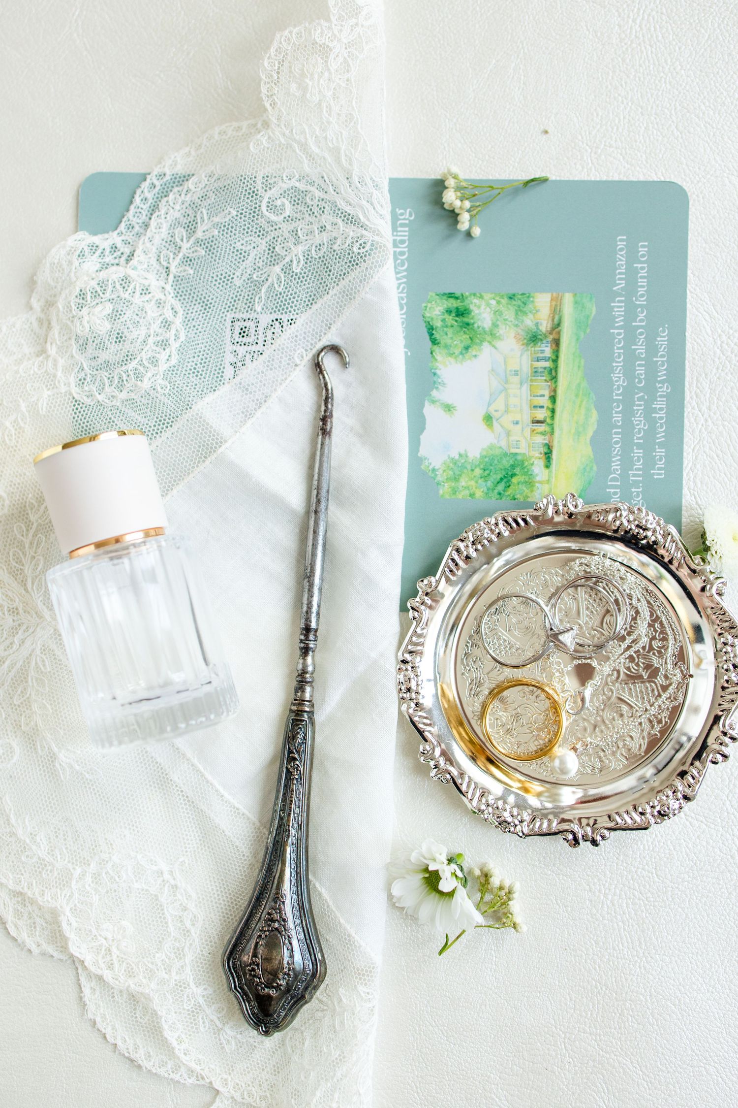 Vintage silver serving spoons and delicate lace doilies arranged with soft blue invitation cards in a romantic styling.