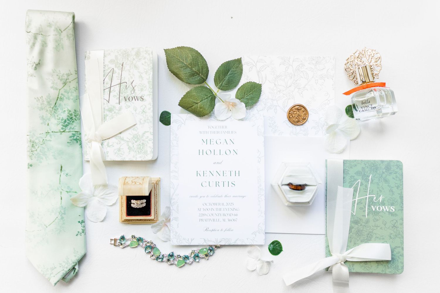Wedding stationery flatlay with green eucalyptus leaves, white invitations and delicate styling elements on light background.