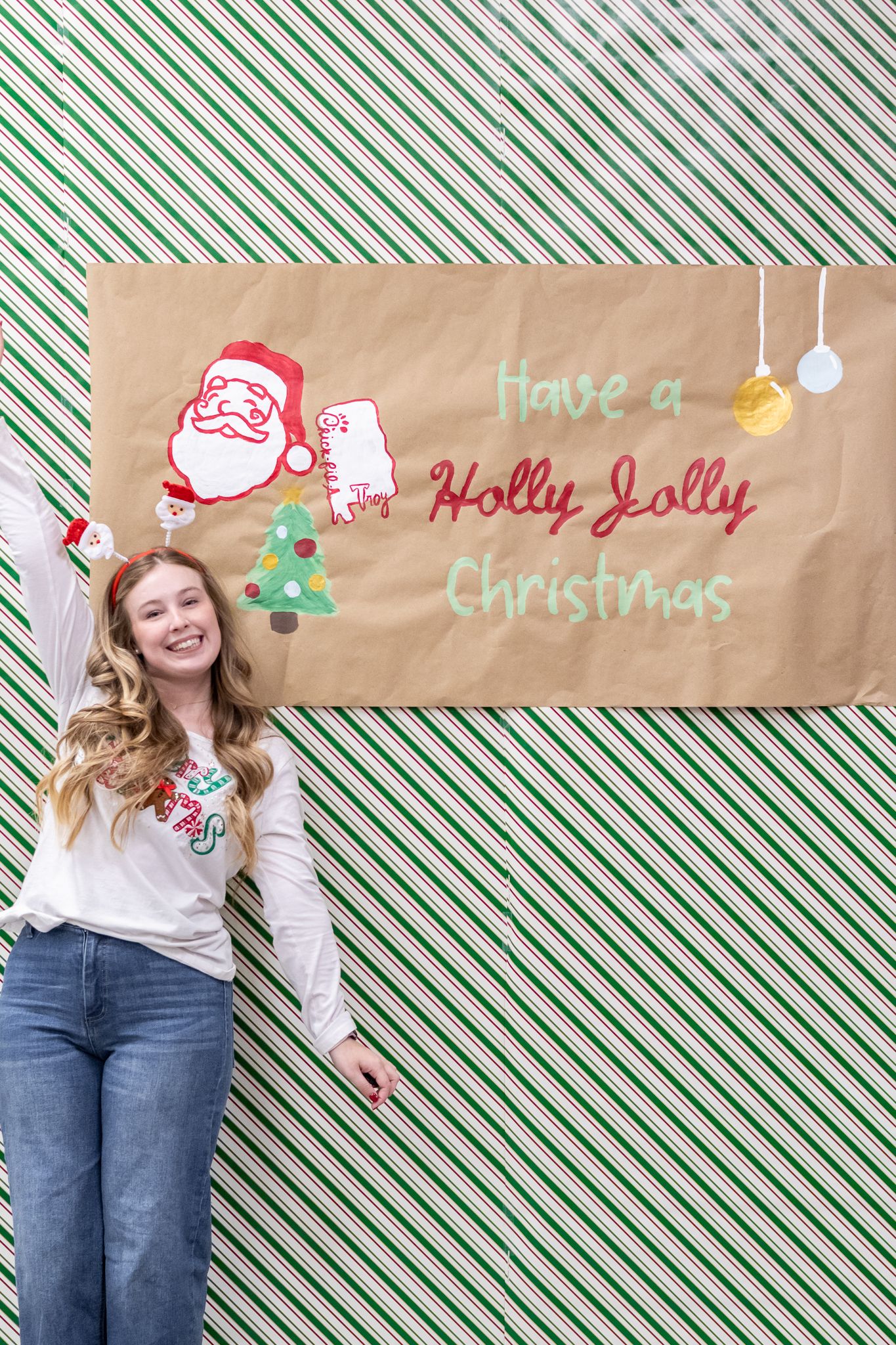 A person in jeans and a white top poses against a striped background with Christmas decorations and text.