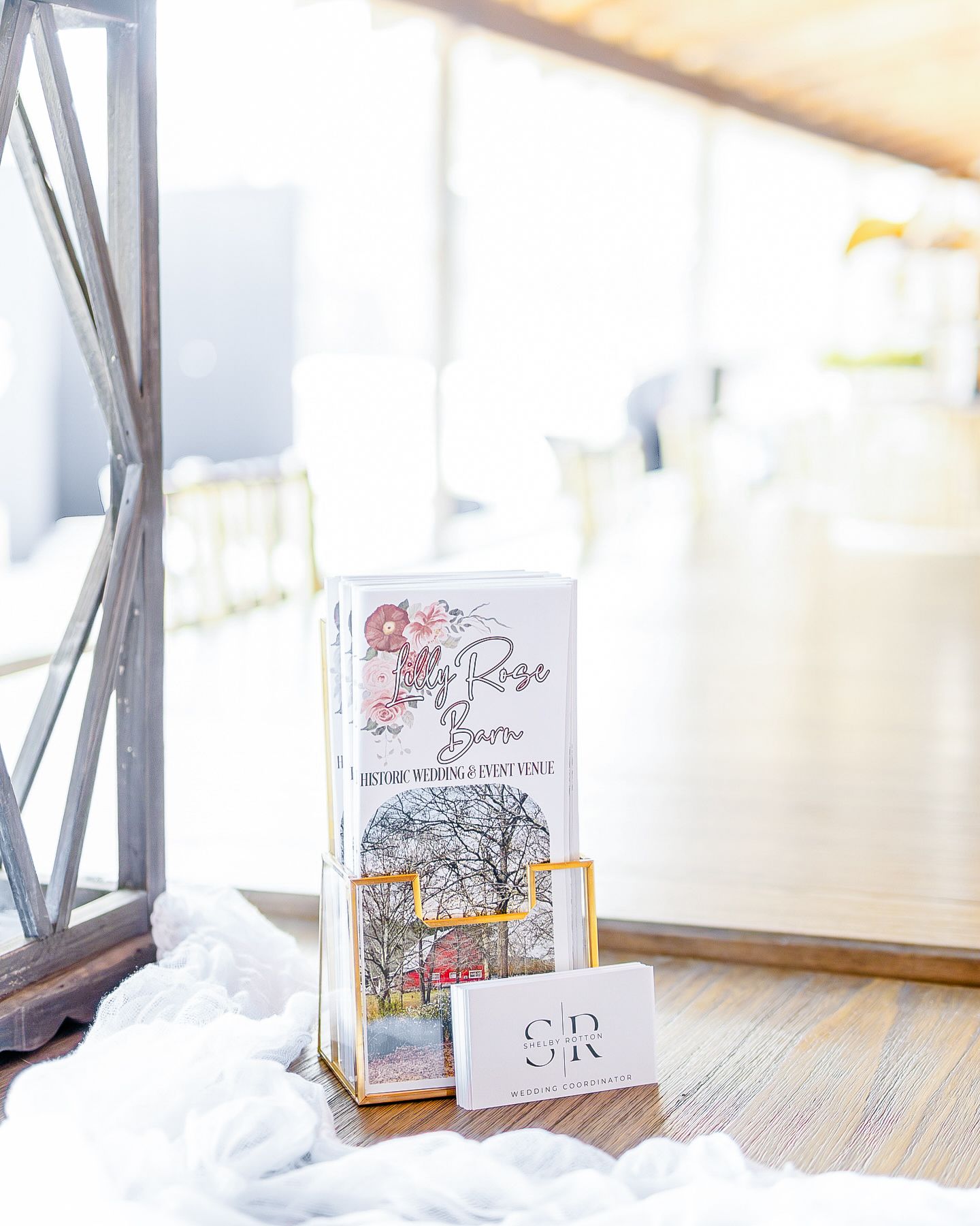 Three white book covers displayed on a wooden surface with soft natural lighting and window reflections.