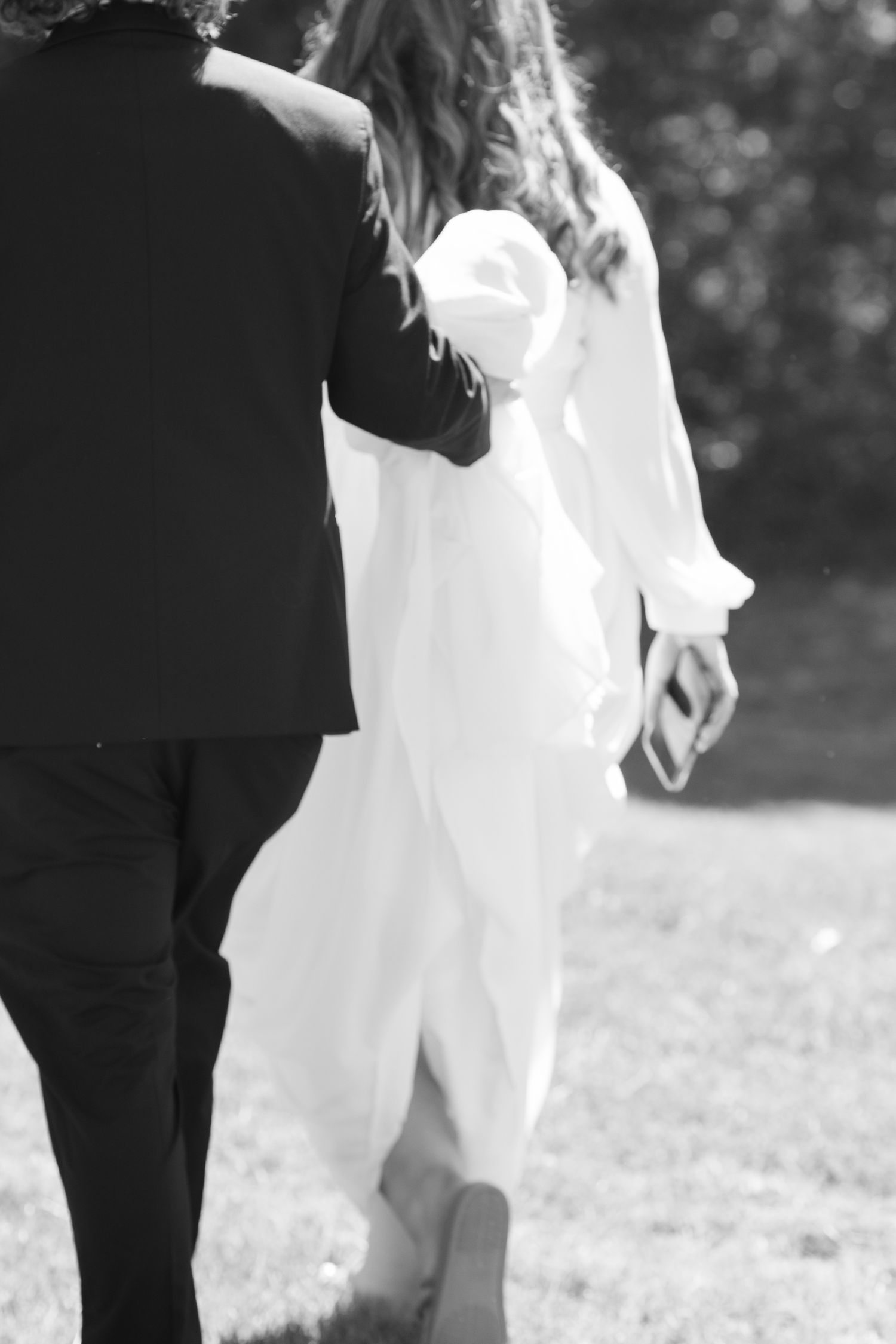 A black and white photo series showing close-up details of a bride and groom walking together outdoors.