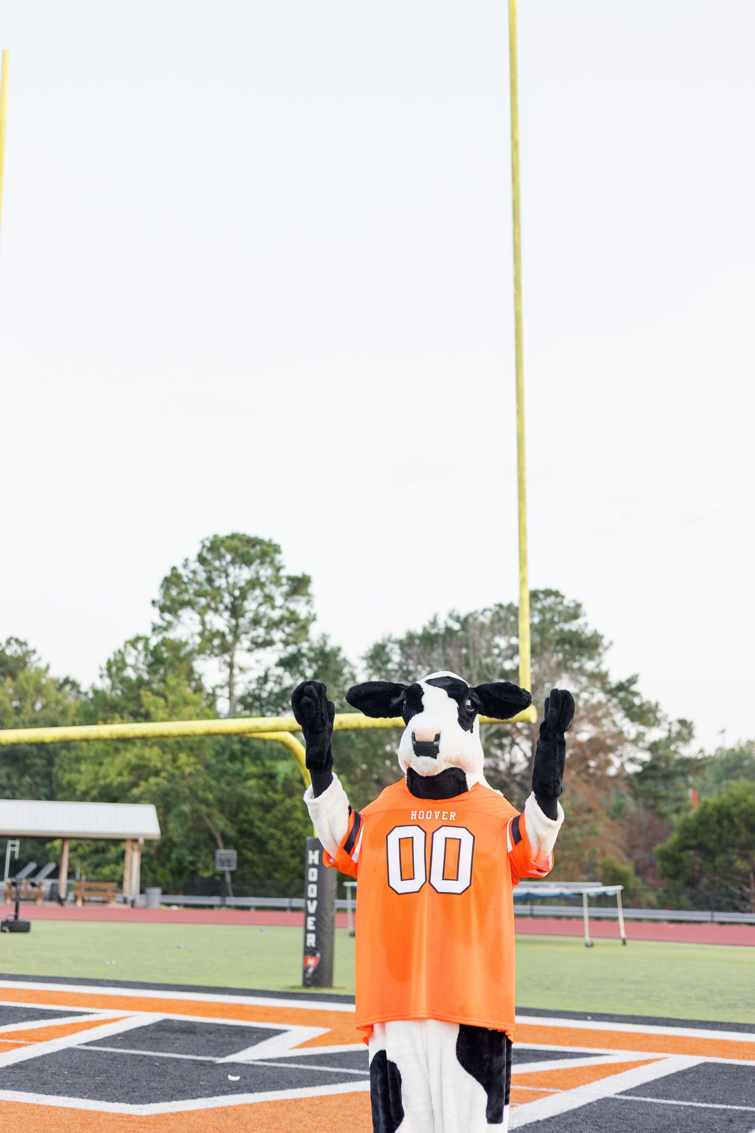 A sequence of four orange football jerseys displayed on a field with goal posts visible in the background.