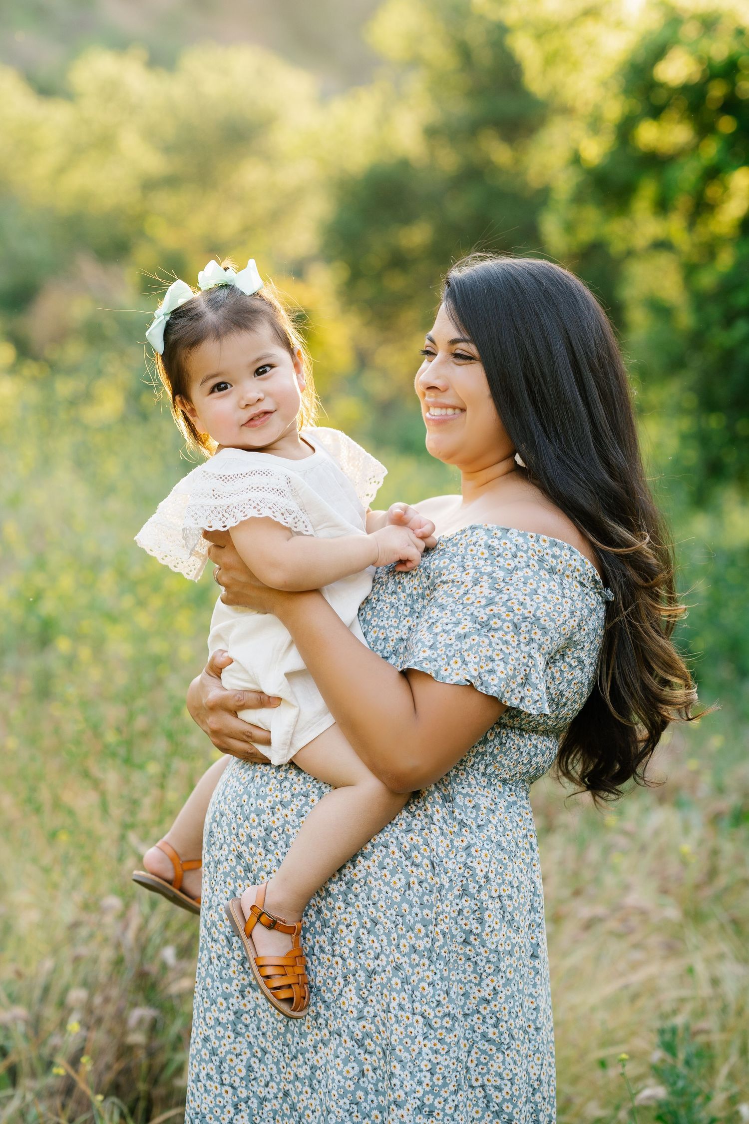 A sweet outdoor portrait in a field with sunlit greenery.
