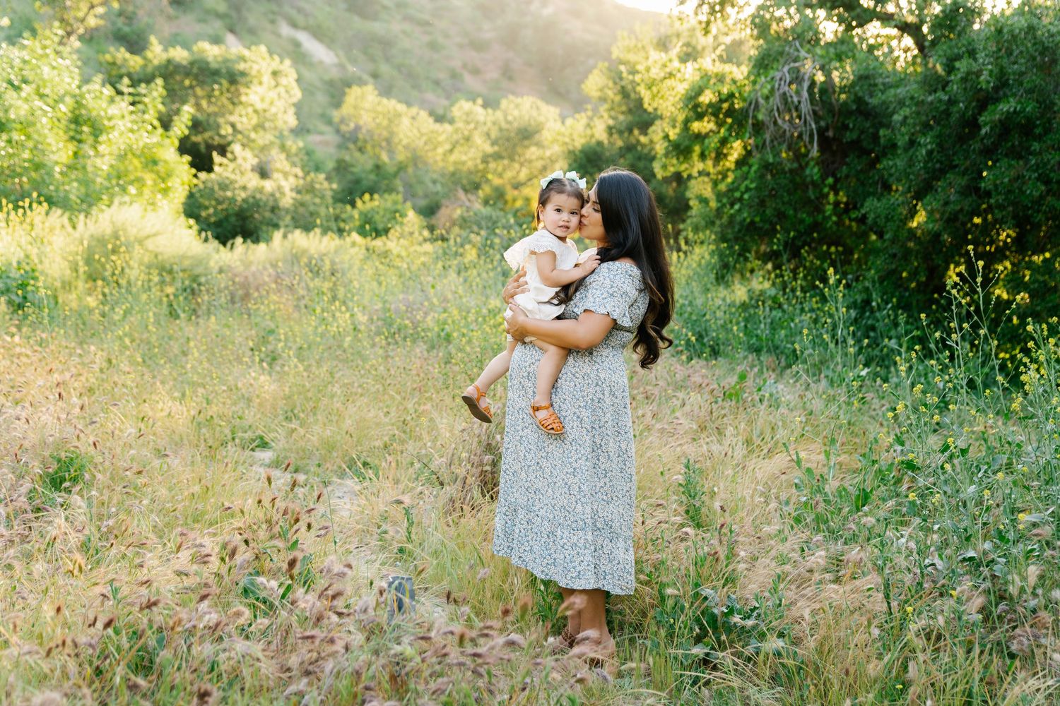 A tender embrace captured in golden sunlight against lush greenery.