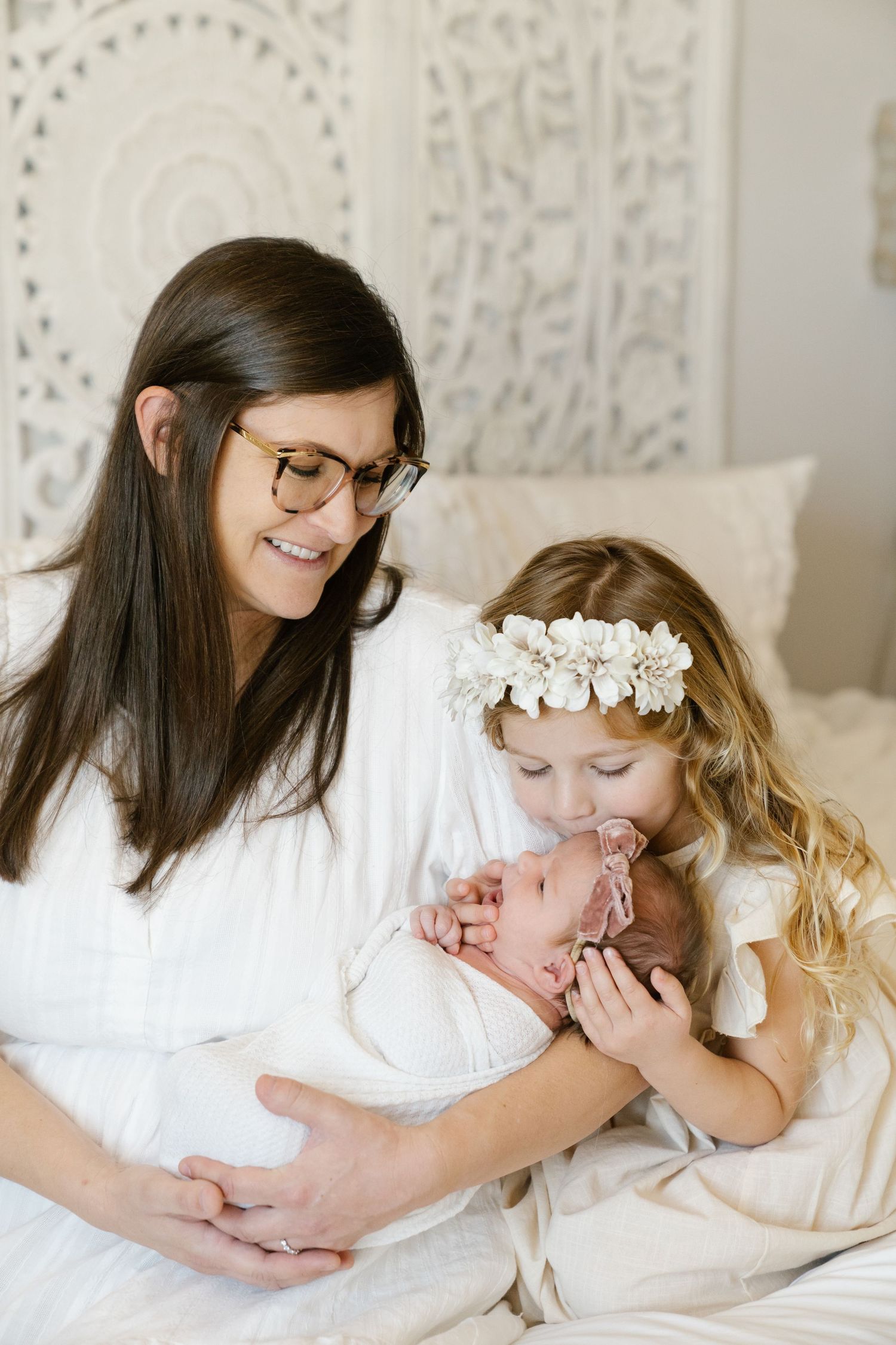 A tender moment shared with a newborn on white bedding.