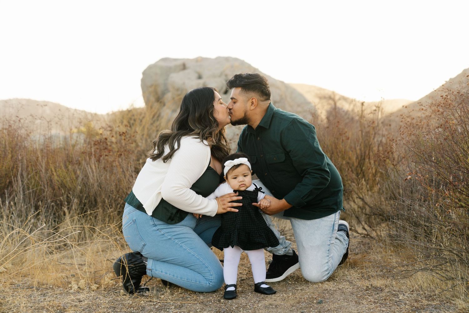 Family sharing tender moment together in desert landscape setting.