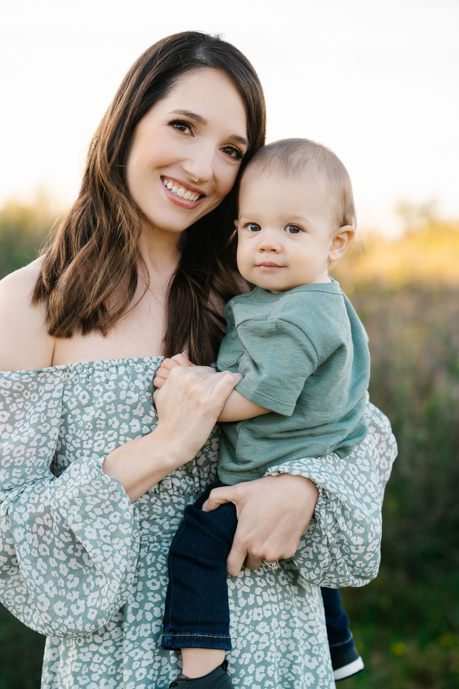 Tender portrait in floral dress against natural outdoor backdrop.