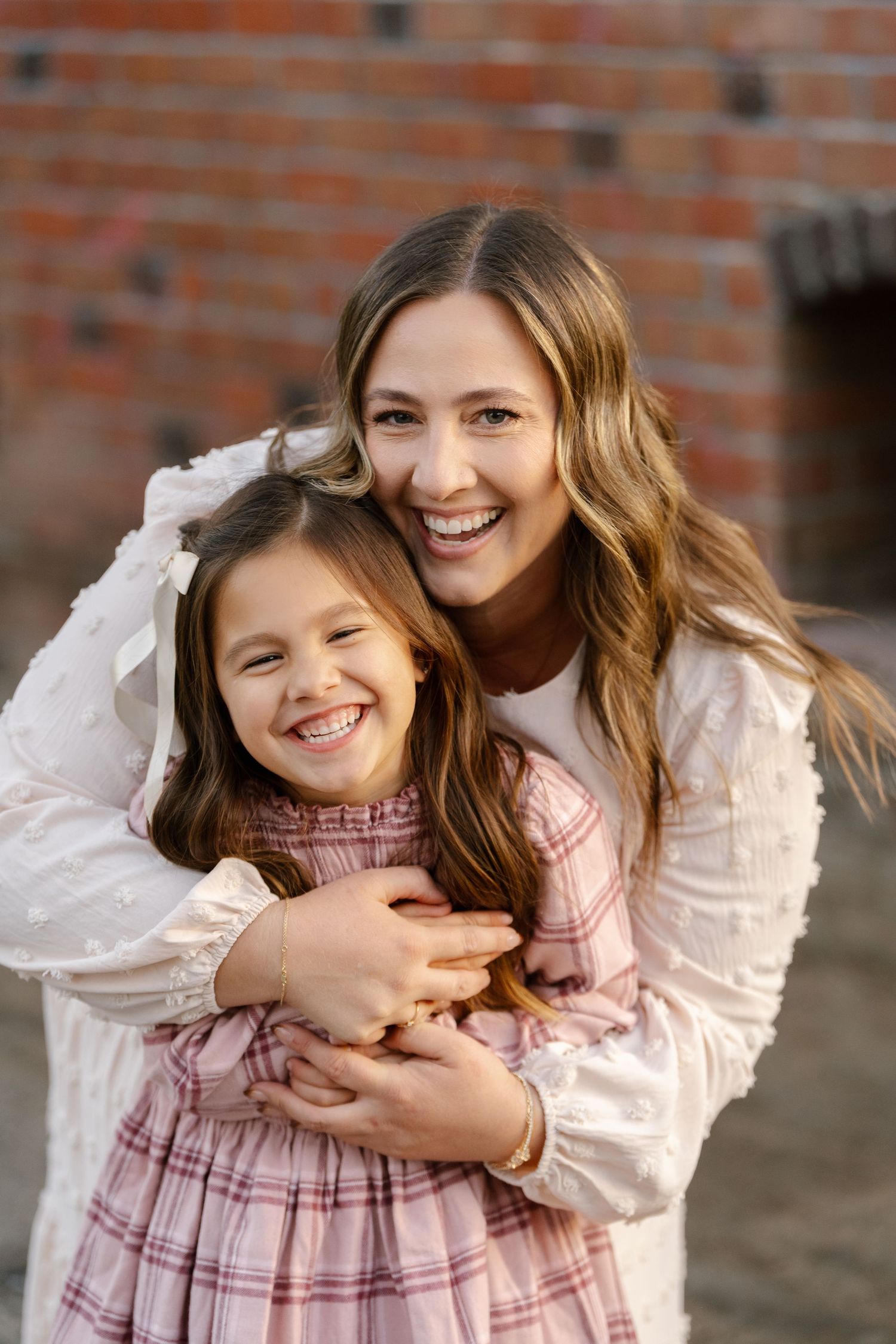 Sweet candid moment between two people against a rustic brick wall.