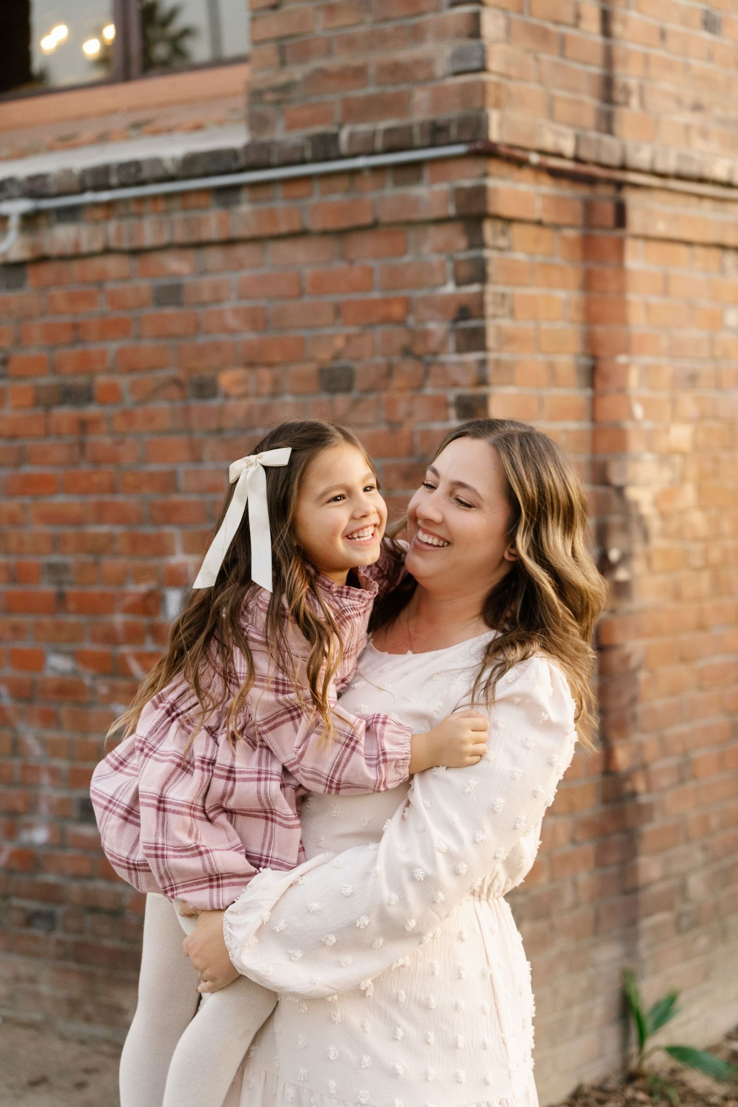 Candid laughing moment captured against brick wall background.