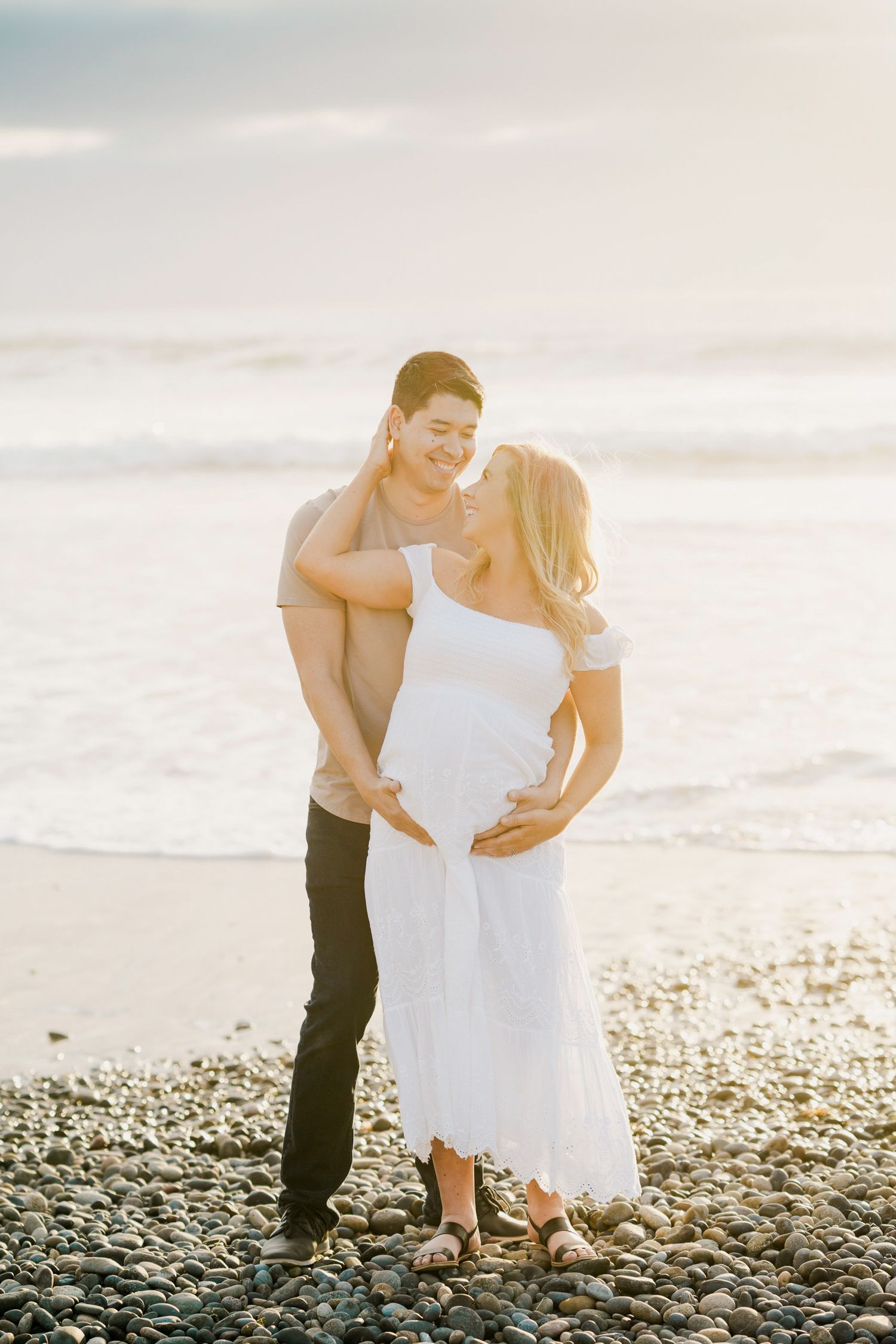 Romantic beachside moment at sunset on a rocky shoreline.