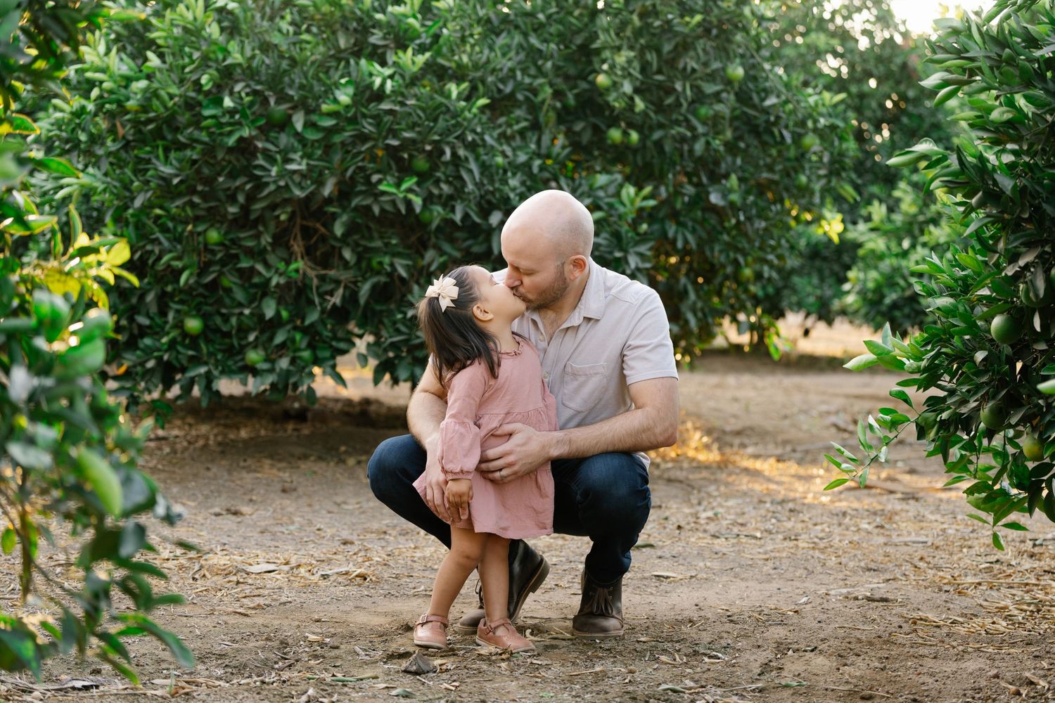 A sweet bonding moment between parent and child in a garden path surrounded by trees.