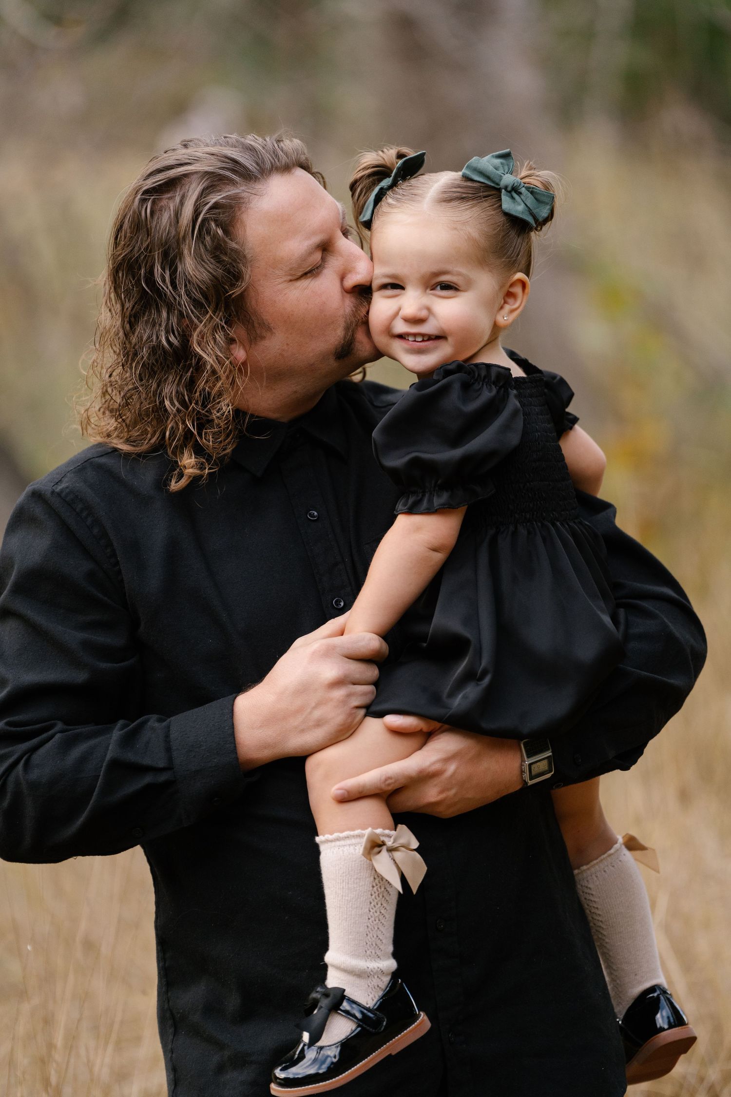 Tender moment captured between parent and child both wearing black outdoors.