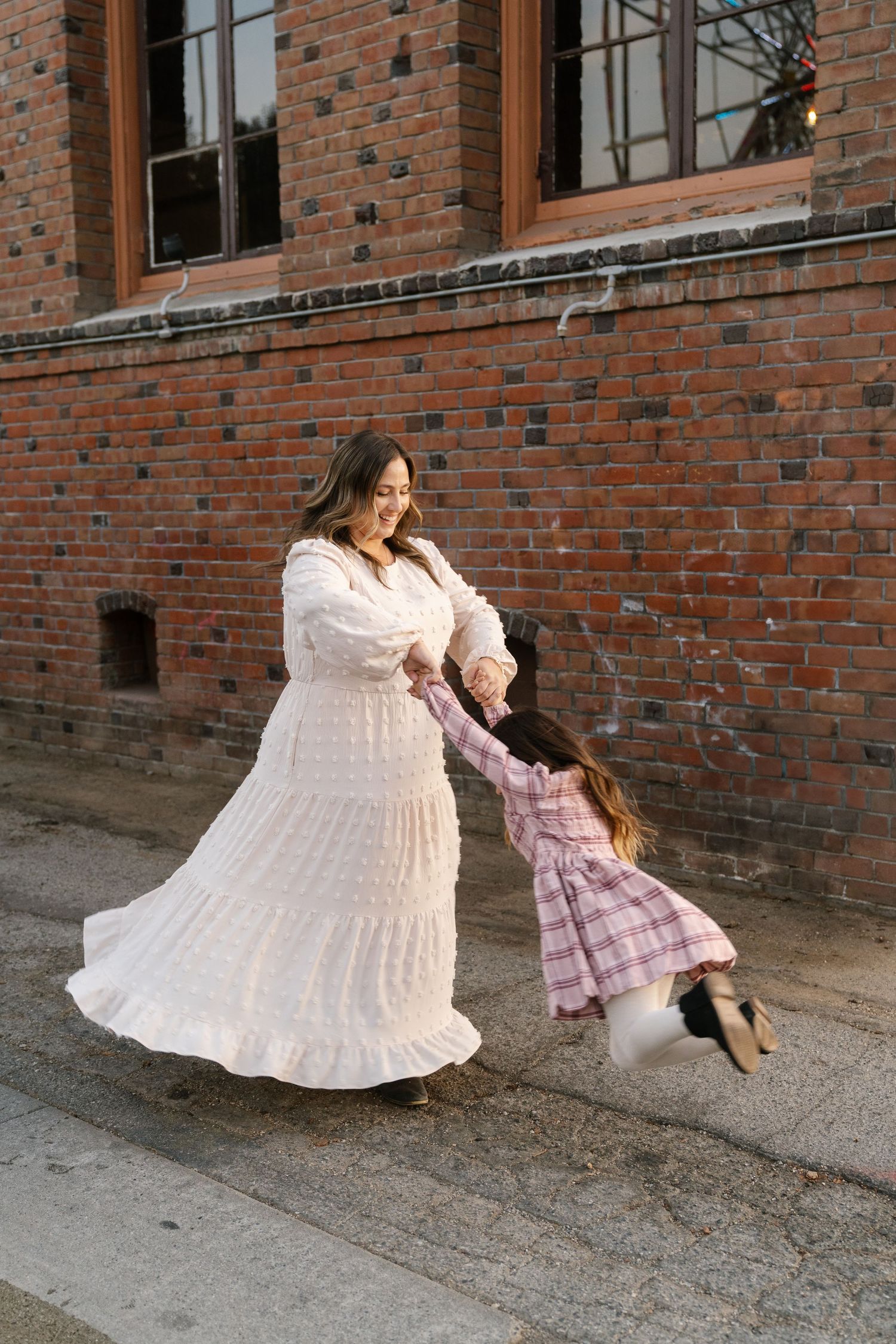 Joyful dancing scene against historic brick building backdrop.