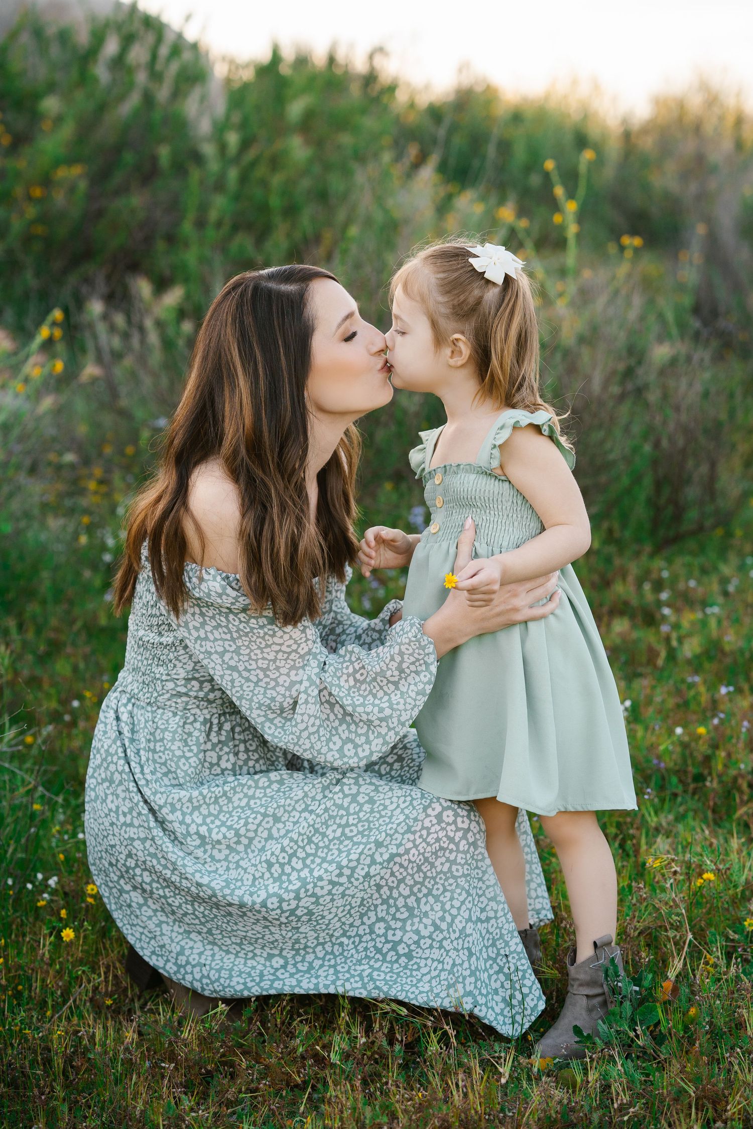 Sweet interaction in floral dress amidst wildflowers during sunset.