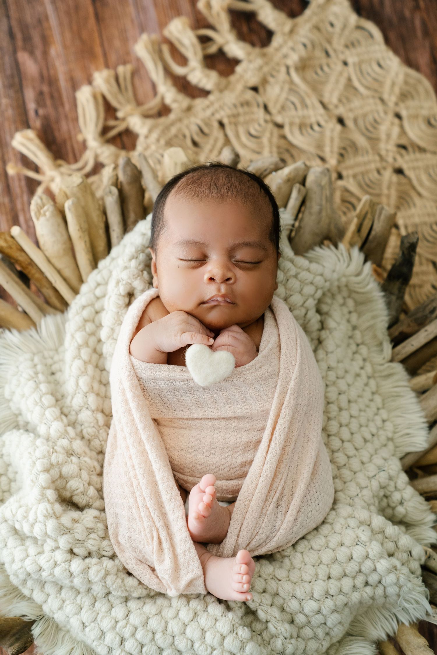 Peaceful sleeping baby wrapped in light fabric on cream knit blanket.
