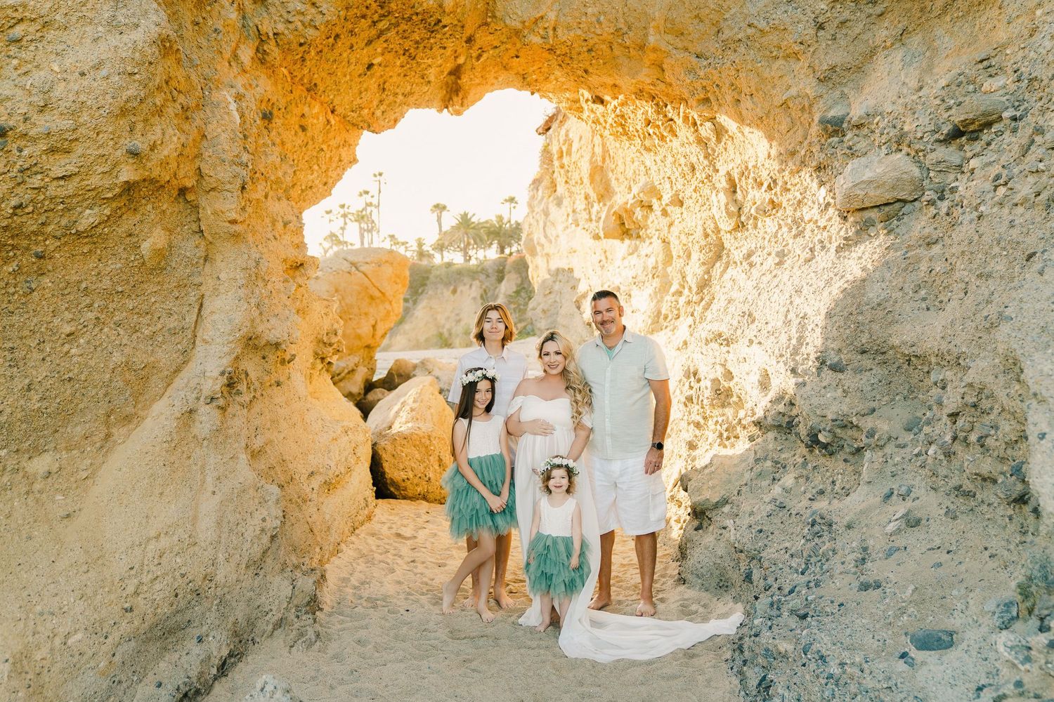 Family standing together in natural rock cave formation with bright sunlit opening.