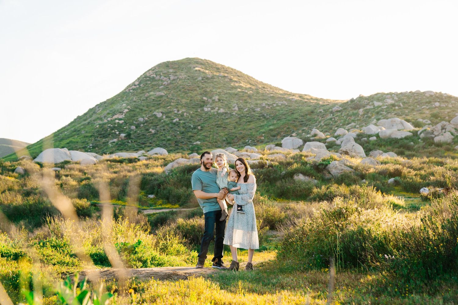 Family portrait against mountain landscape during golden hour.
