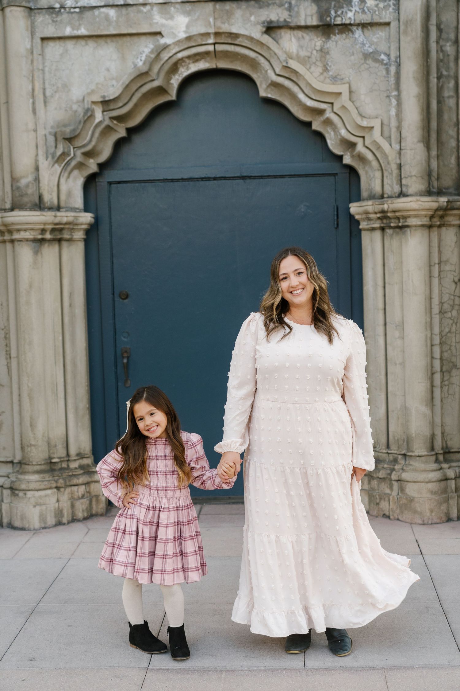 Beautiful portrait in front of a historic blue door in elegant white and pink dresses.