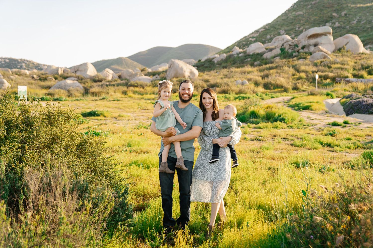 Family walking together through mountainous field with golden grass and rocks.