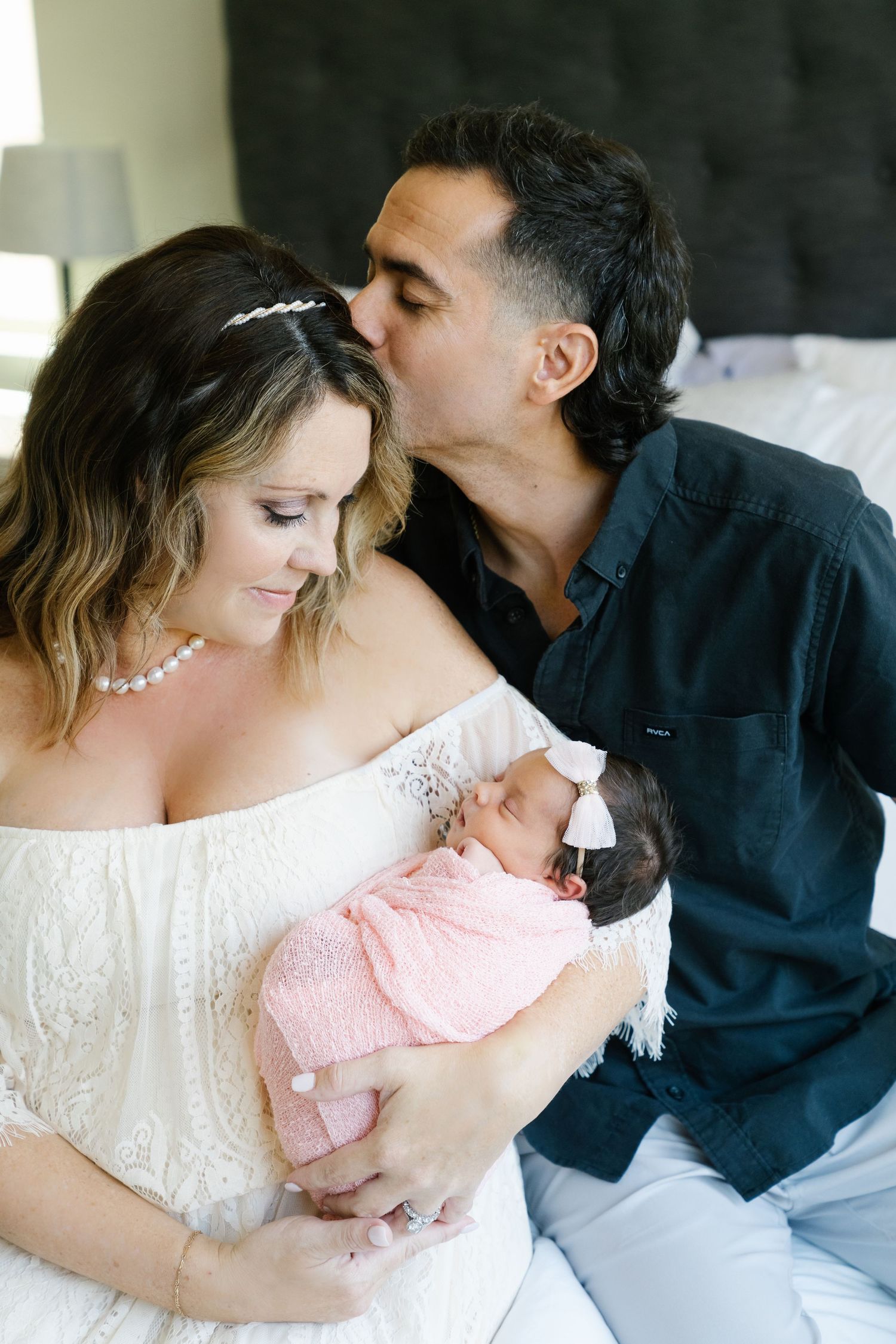 Intimate family portrait showing tender moment with young baby in pink clothing.
